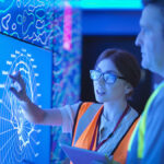 Female geologist with colleague studying graphical display of oil and gas bearing rock on screens